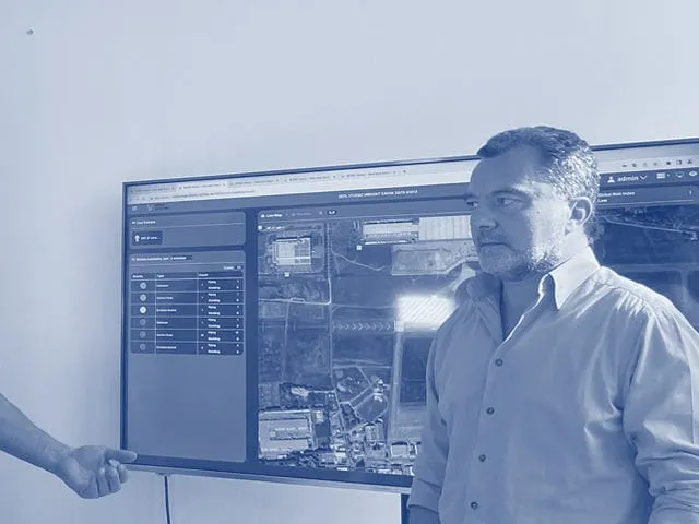 At work in the lab, a hand pointing at the wall screen and a man listening, printed in blue duotone