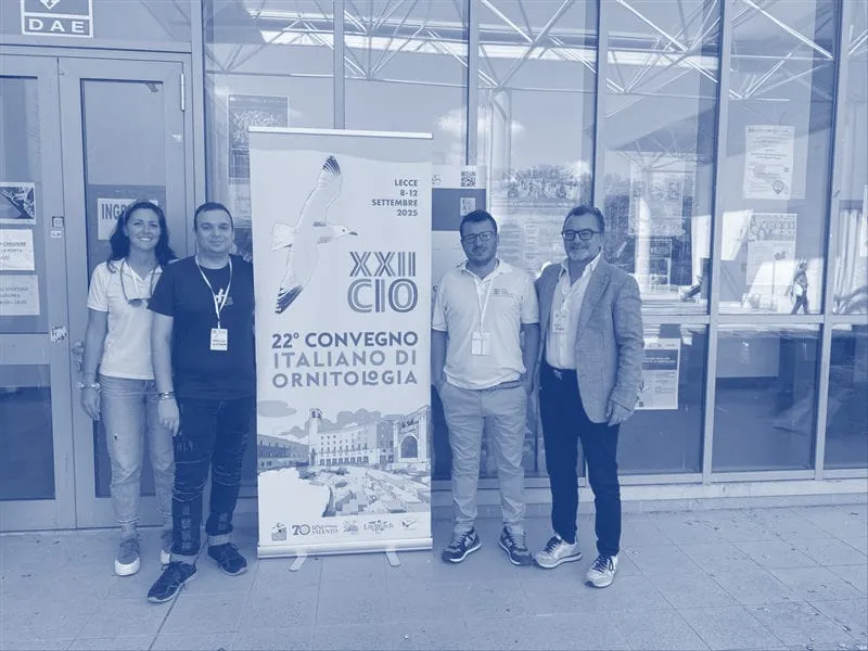The team and the biologists standing by the congress banner in Lecce, printed in blue duotone