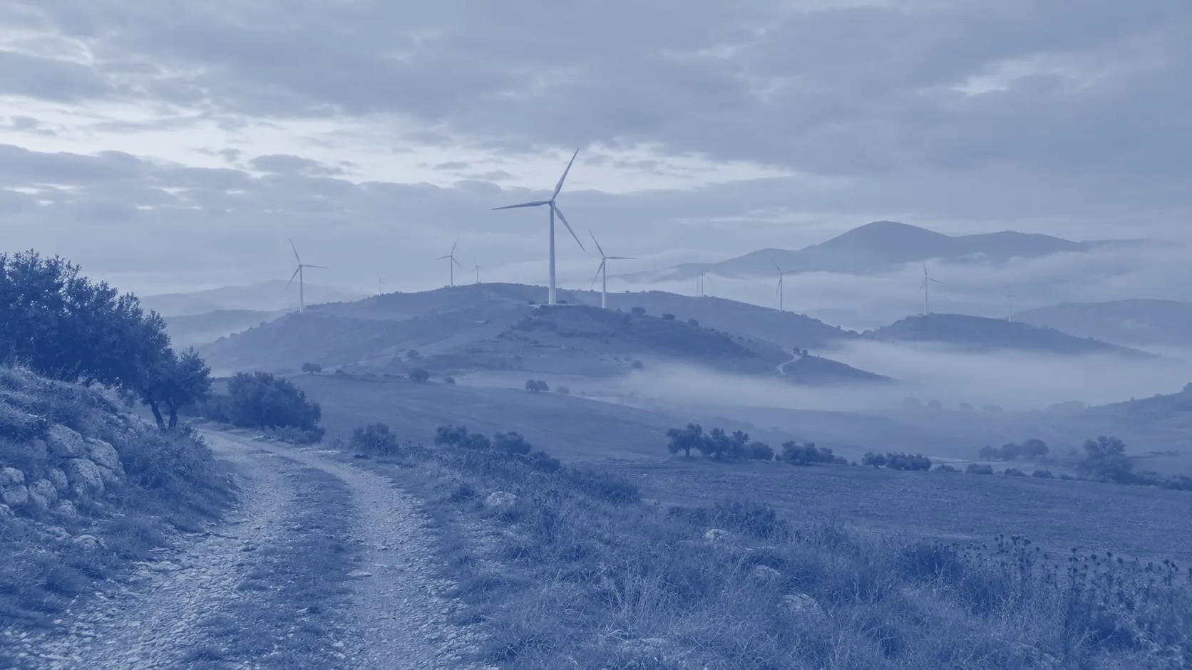 Wind turbines on rolling hills in the morning mist, a farm road in the foreground, an illustration printed in blue duotone